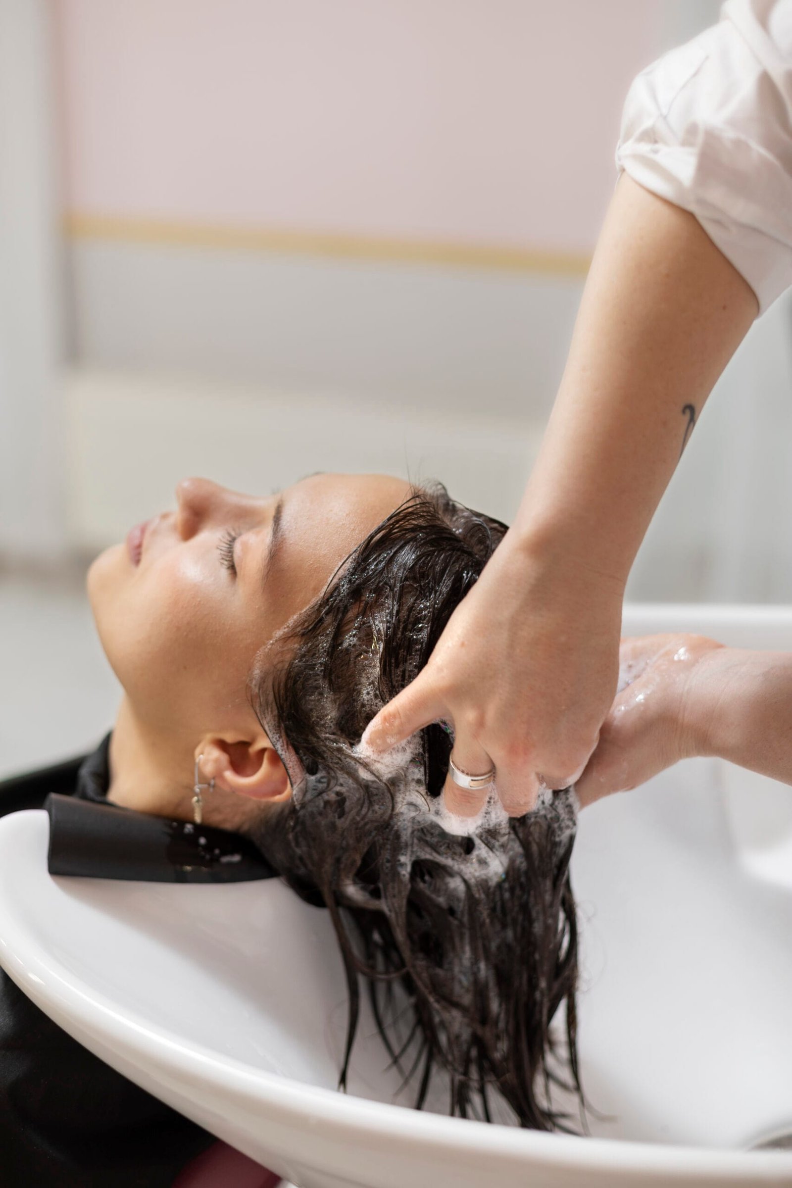 FEMME-RECEVANT-UN-TRAITEMENT-AU-SALON-DE-COIFFURE Image de produits capillaires pour un soin