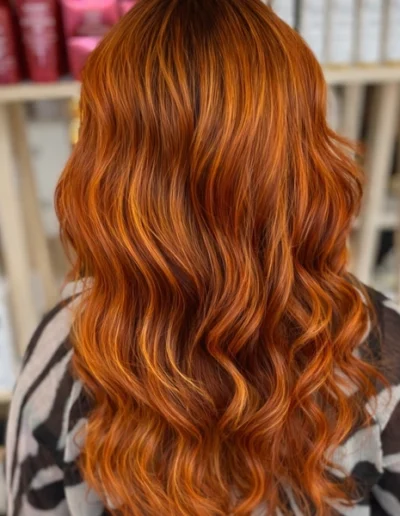 Coloration cuivrée sur cheveux longs ondulés réalisée par un coiffeur coloriste à Clermont-Ferrand