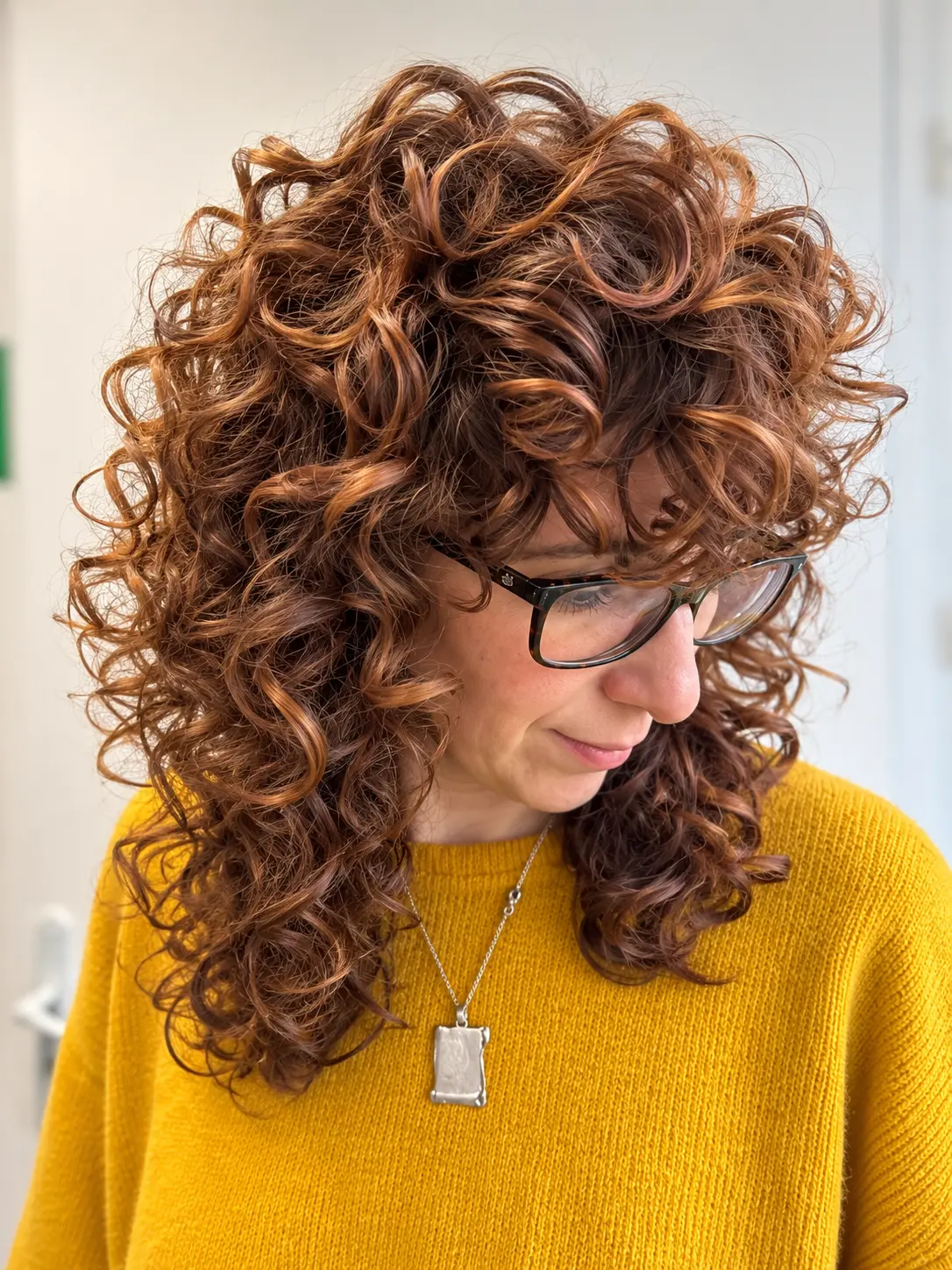 Boucles cuivrées et volumineuses avec frange, cliente à lunettes